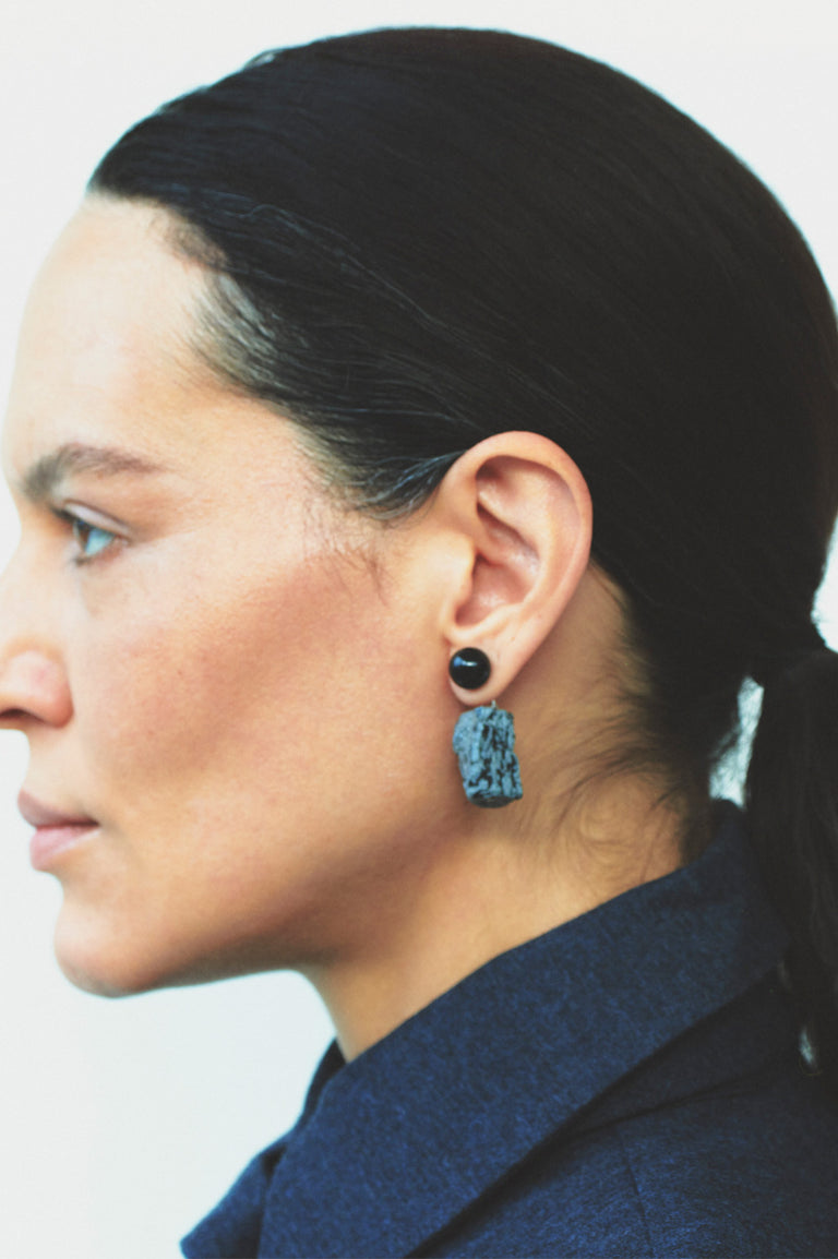 Close-up of a person wearing a blue earring with a black center.
