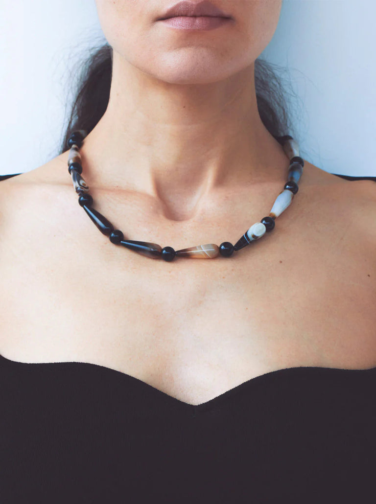 Necklace with black and white beads worn by a person against a neutral background